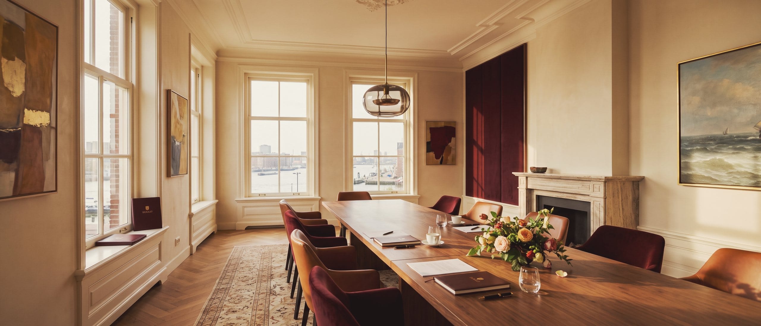 A long meeting table just after an agreement was signed, with the chairs pushed back and the river beyond the windows.